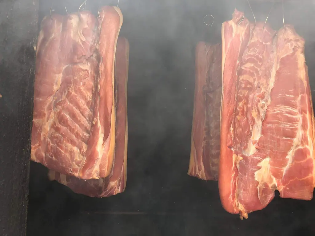 Home-smoked bacon hanging in the smoker at De Klomp Homestead