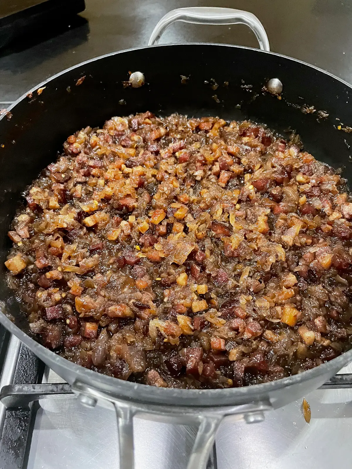 Thick dark bacon jam with caramelised onions and smoked bacon pieces near the end of cooking